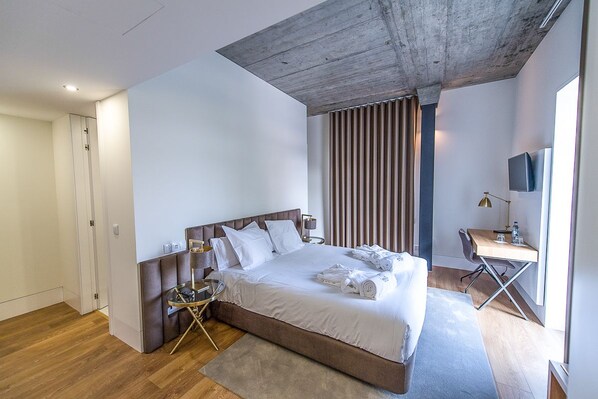 Ein modernes Hotelzimmer mit einem großen Bett, einem Schreibtisch und einem Fernseher.