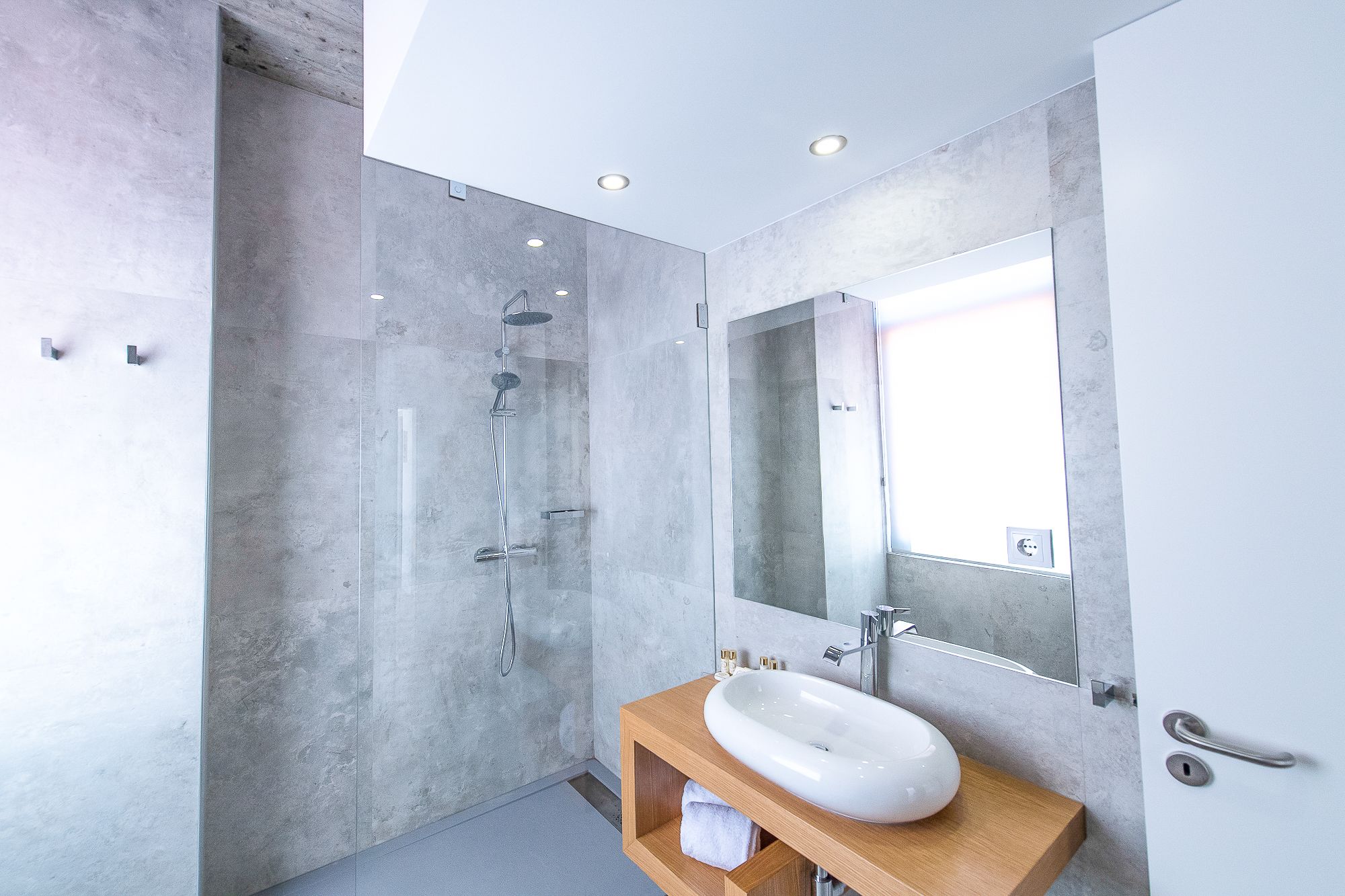 A modern bathroom with a large mirror, a white sink, and a shower.
