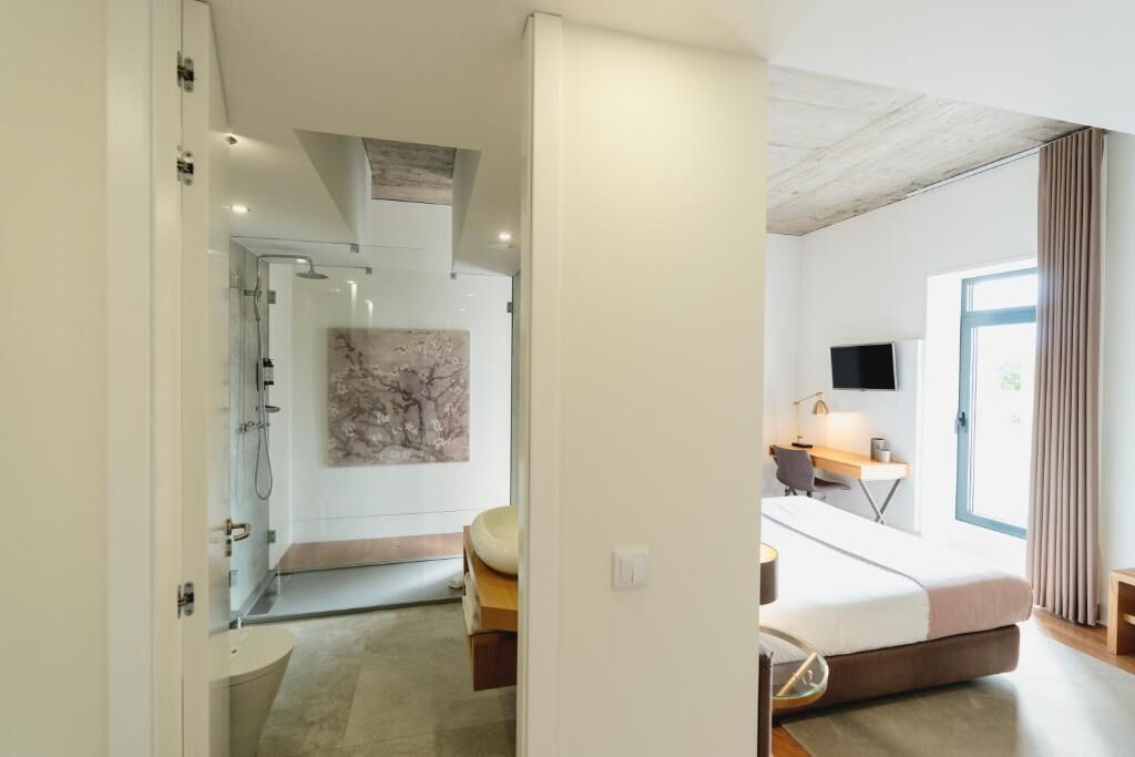 Una habitación de hotel moderna con cama, escritorio y zona de ducha.