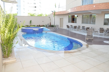 Una piscina al aire libre, sombrillas, sillones reclinables de piscina. Lotus Hotel