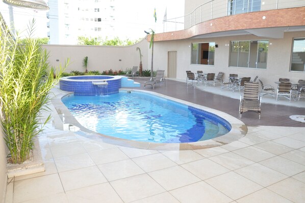 Una piscina al aire libre, sombrillas, sillones reclinables de piscina