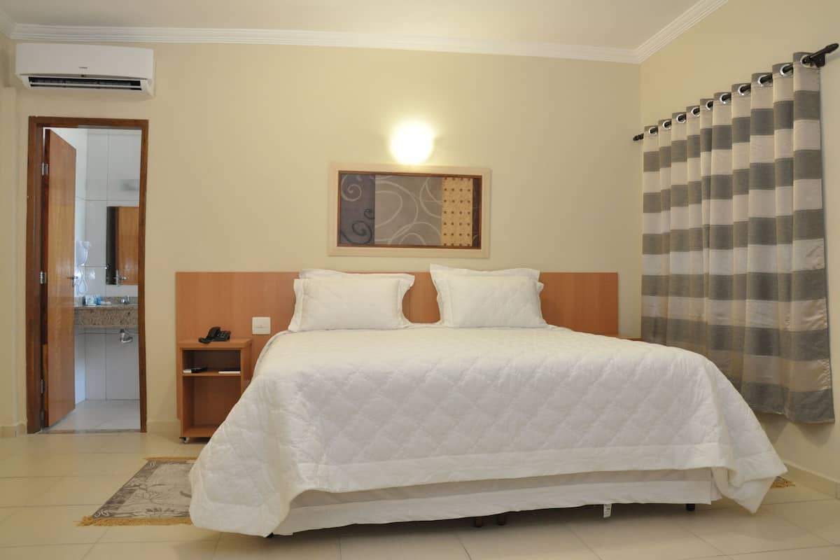Un dormitorio ordenado con cama, mesita de noche y una lámpara de pared.