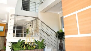 A modern interior with a staircase, metal railings, and potted plants.