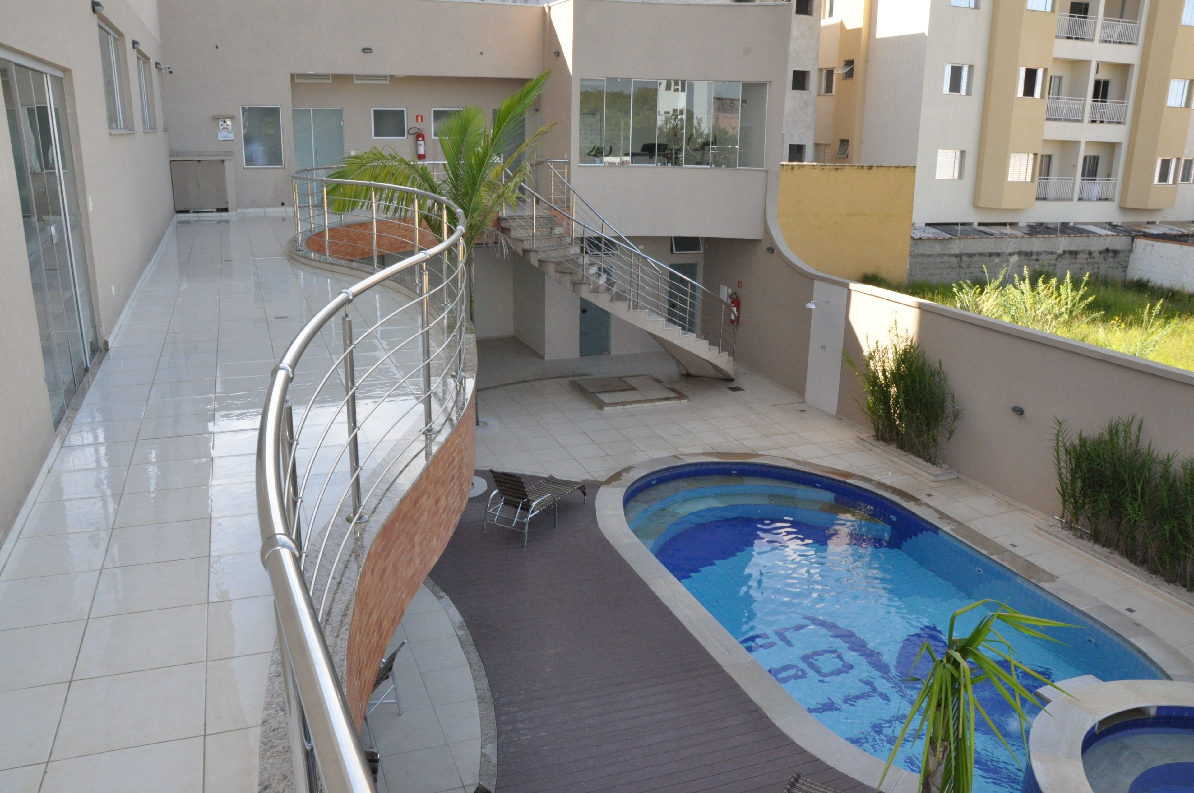 A swimming pool with a wooden deck, a metal railing, and a staircase leading to an upper level.