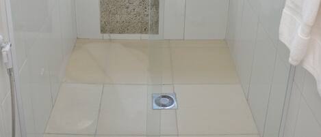A small, enclosed shower area with a bathtub, a window, and a towel hanging on the wall.