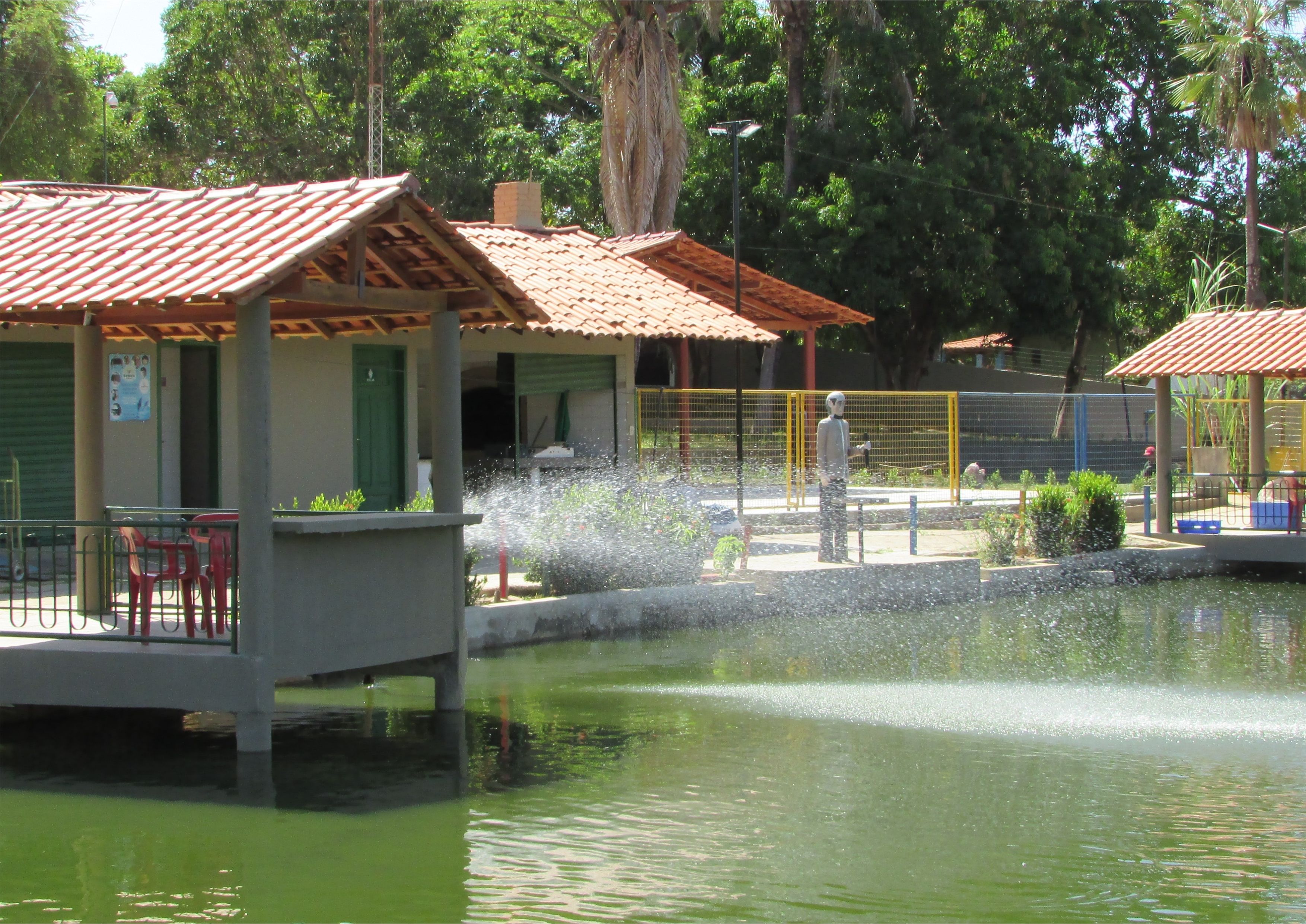 A water feature with a fountain, surrounded by a pool and a pavilion with a tiled roof.