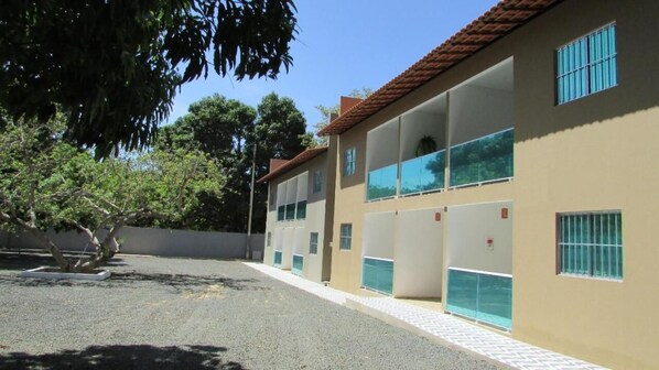 Un edificio con varios balcones, amplias ventanas y un patio empedrado.