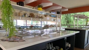 A modern kitchen with a central island, black cabinetry, and a variety of kitchen utensils and appliances. - Resort Hotel Atlantic City Náutico Clube (Teresina)