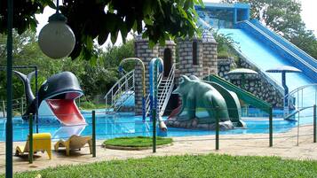 Un parque acuático con toboganes, una piscina y un edificio al fondo.