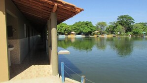 A covered walkway leading to a pool area with a view of a calm lake and trees in the background. - Resort Hotel Atlantic City Náutico Clube (Teresina)