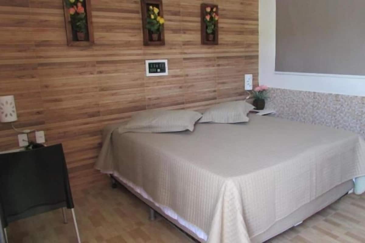 A bedroom with a bed, a small table, and a wall-mounted light fixture.