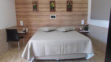 Un dormitorio ordenado con cama, una silla y una mesita de noche con lámpara.