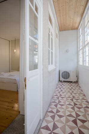 A narrow hallway with a geometric patterned floor, white walls, and a wooden ceiling. - Liiiving in Porto - Bolhão Market Apartment II (Porto)