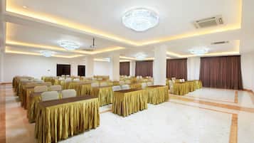 A conference room with rows of tables, chandeliers, and a marble floor.