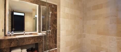 A modern bathroom with a glass-enclosed shower, a large mirror, and a marble countertop.