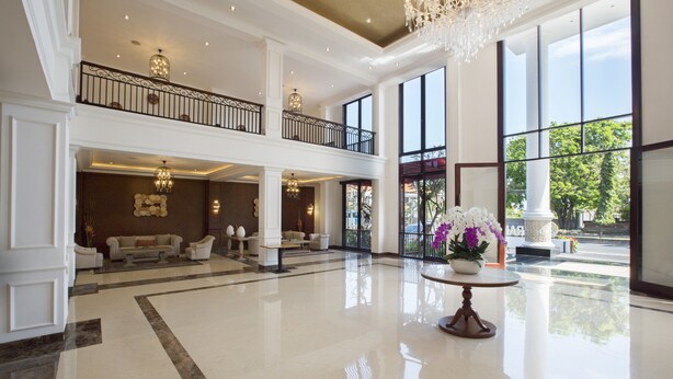 A spacious lobby with a high ceiling, large windows, and a chandelier.