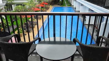 A balcony with a pool, wicker chairs, and a table.