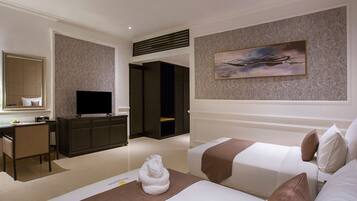 A hotel room with two beds, a desk, a television, and a painting on the wall.