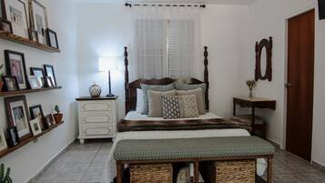 Une chambre à coucher avec un lit, des tables de chevet, un lustre, un miroir fixé au mur et une plante en pot.