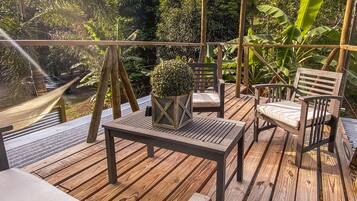 A wooden deck with a hammock, a table, and two chairs.