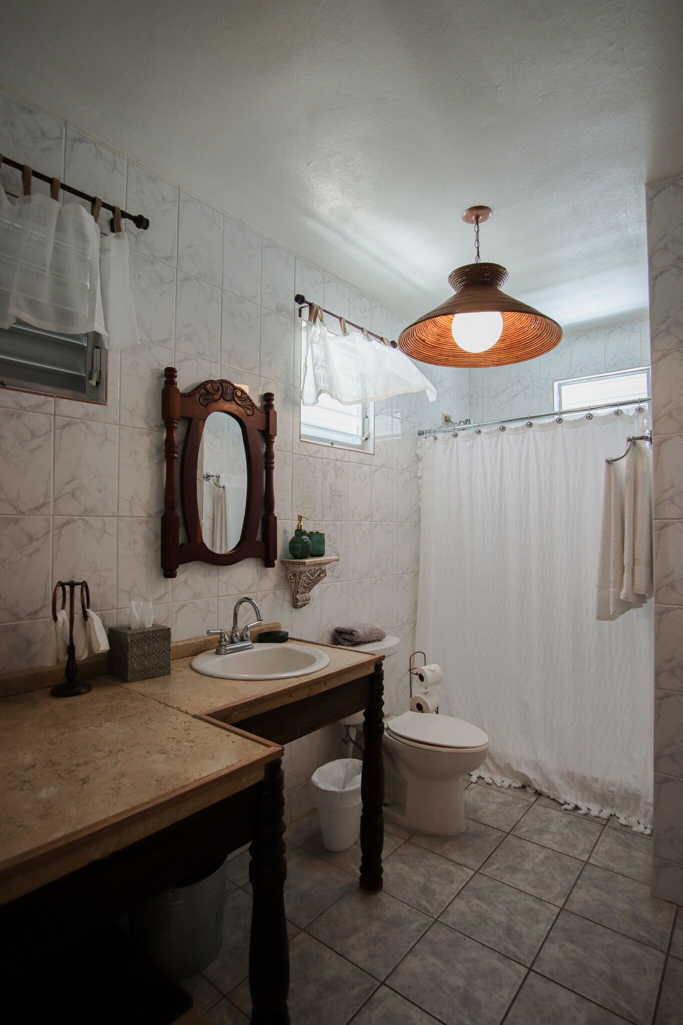 A bathroom with a wooden vanity, a mirror, a sink, a toilet, and a shower curtain.