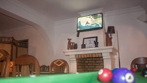 A billiards table with balls, a fireplace, a television, and wooden furniture in a room. - Iarimbato Hotel (Antananarivo)