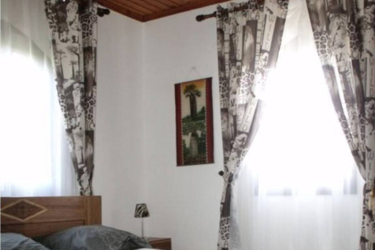 A bedroom with a wooden bed, patterned curtains, and a framed picture on the wall.