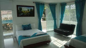 Una habitación de hotel con una cama, un sofá y un balcón con cortinas azules.