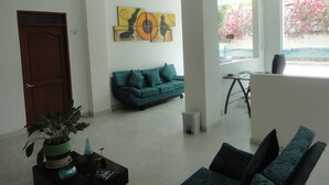Un salón moderno con un sofá verde, una mesa de centro con adornos, un cuadro en la pared y una ventana con vistas a flores rosadas.