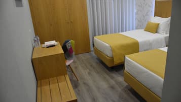 Una habitación de hotel con dos camas, un escritorio de madera, una silla y una ventana con cortinas.
