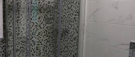 A bathroom with a glass-enclosed shower, a bidet, and a toilet.