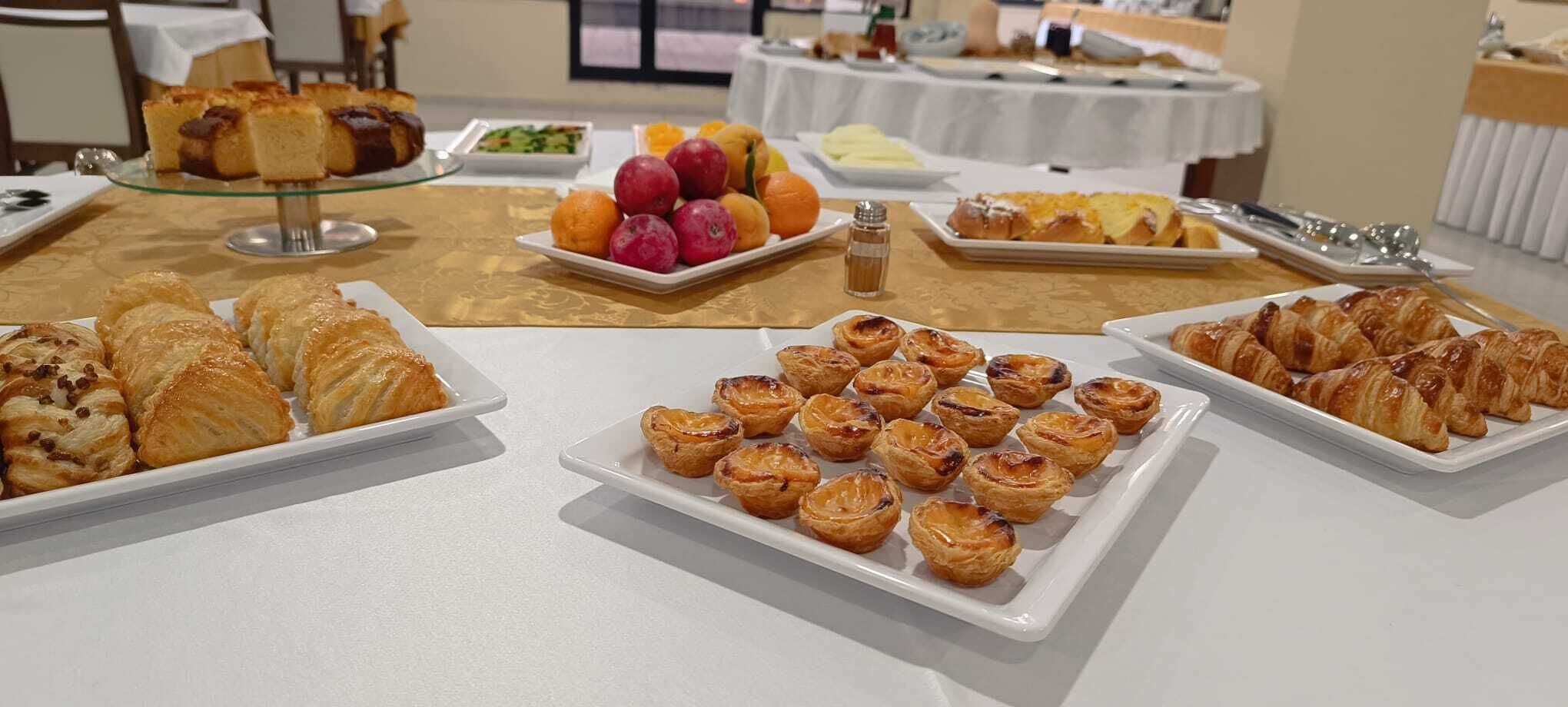 Egy svédasztal, melyen különféle sütemények – többek között croissant-ok és piték – és egy válogatott gyümölcs kínálat található.