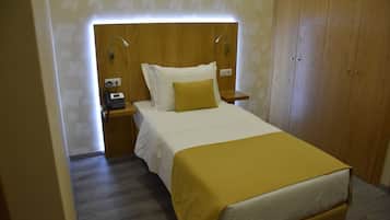 A neatly arranged bedroom with a bed, bedside tables, and a telephone.