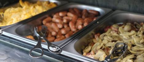 Un bufé con diversas opciones de comida, incluyendo frijoles, huevos y vegetales.