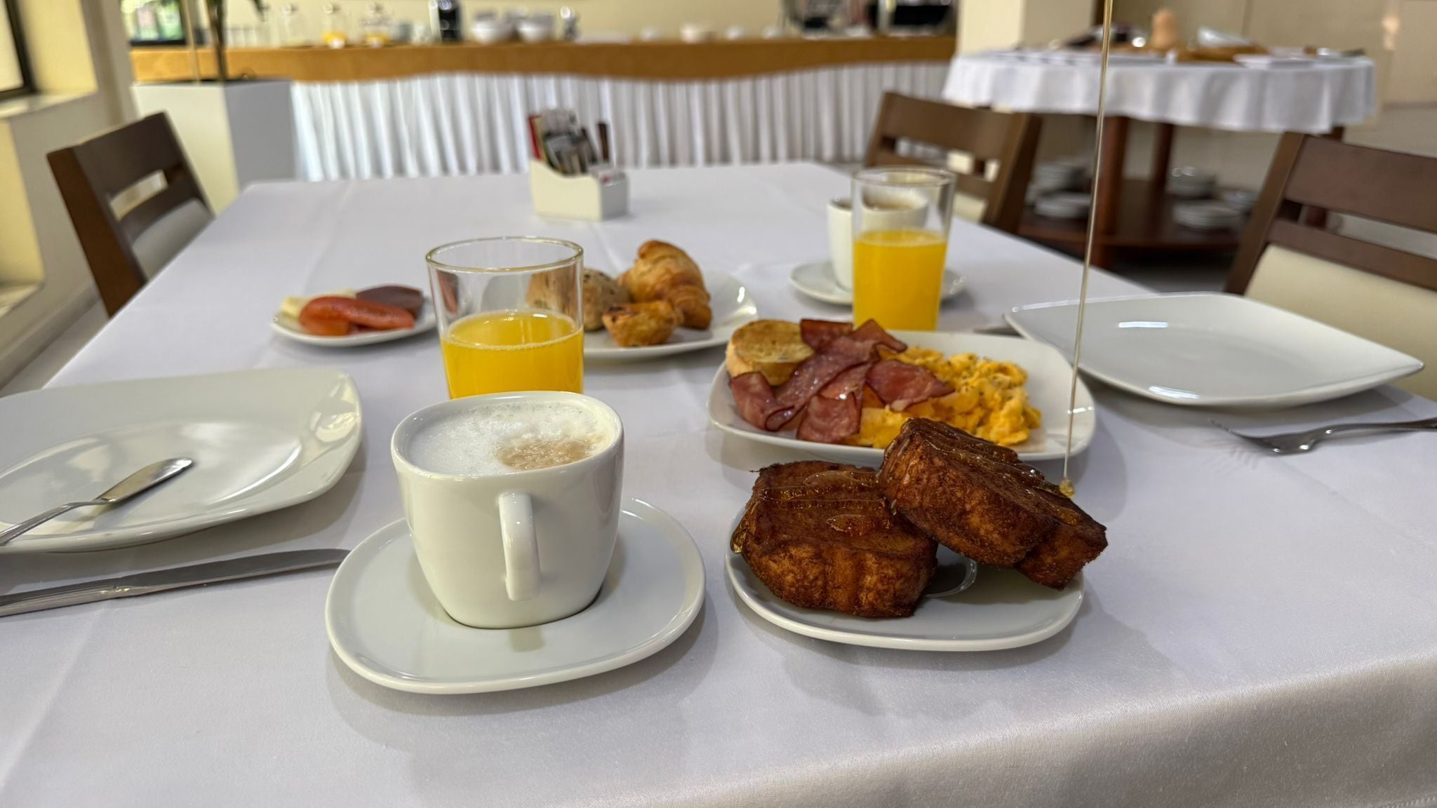A breakfast setting with plates of food, a cup of coffee, and a glass of orange juice on a table.