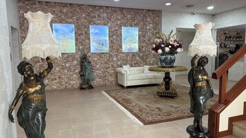 Un hall con pared de piedra, un sofá blanco, una mesa decorativa con un jarrón y una escalera.