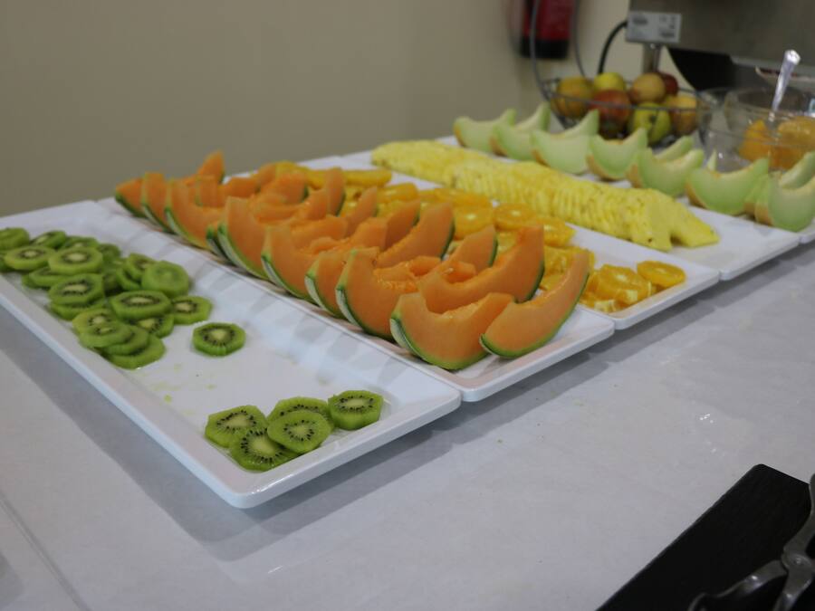 Un bufé con frutas en rodajas, incluyendo kiwi, melón y piña.