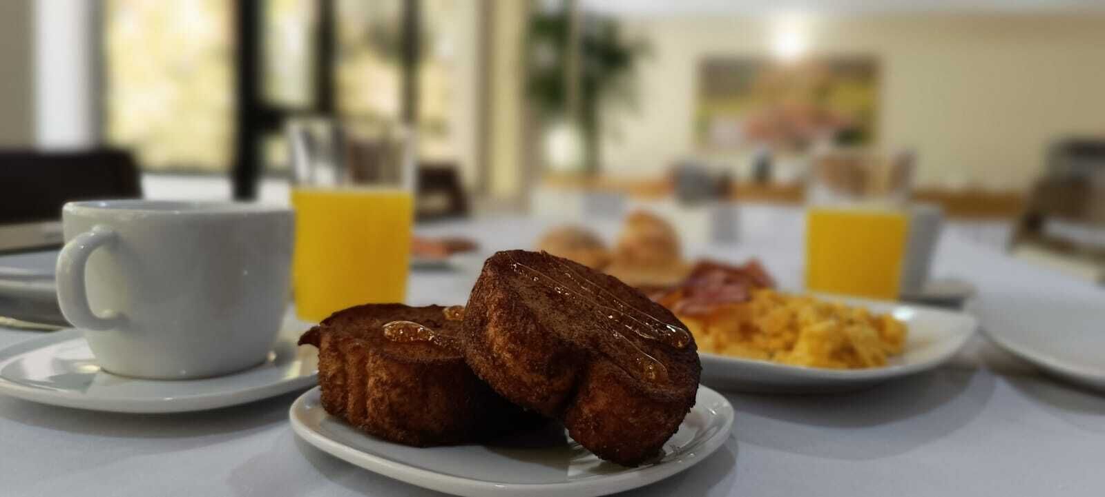 A breakfast setting with a plate of scrambled eggs, a cup of coffee, and a glass of orange juice.
