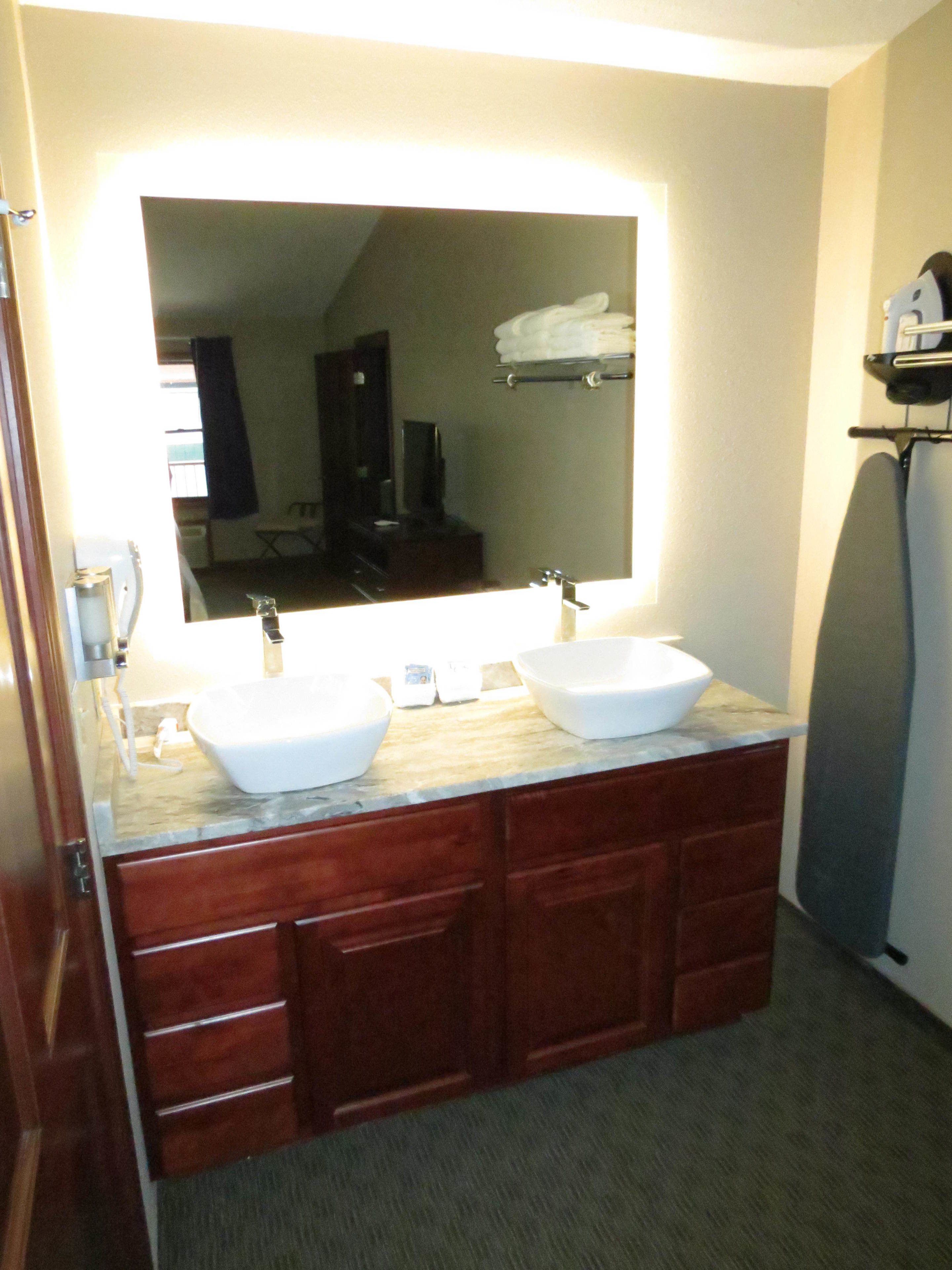 A bathroom with two sinks, a large mirror, and wooden cabinets.