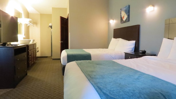 A hotel room with two beds, a desk with a computer, a mirror, and a door leading to another room. - Edgewater Hotel (Put-in-Bay)