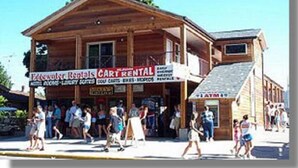 A wooden building with a sign for 'Edwalt Rentals Cart Rental' and an ATM. - Edgewater Hotel (Put-in-Bay)