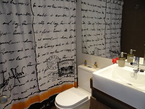 Une salle de bain équipée d’un lavabo, de toilettes et d’un rideau de douche orné d’un texte écrit à la main.
