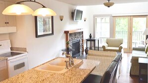 A kitchen with a granite countertop, a built-in oven, and a fireplace. There is a dining area with a table and chairs. - The Cottages on Salt Spring Island (Salt Spring Island)