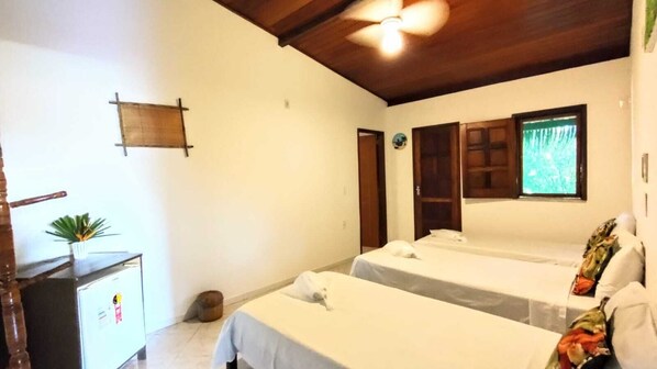 A room with two beds, a wooden ceiling, a small desk with a plant, and a window with a view. - Pousada Sossego Boipeba (Cairu)