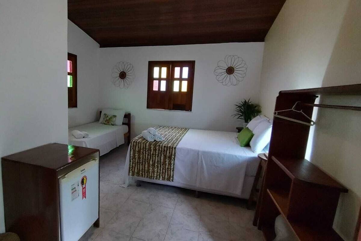 A small, compact room with a bed, a desk, and a refrigerator.