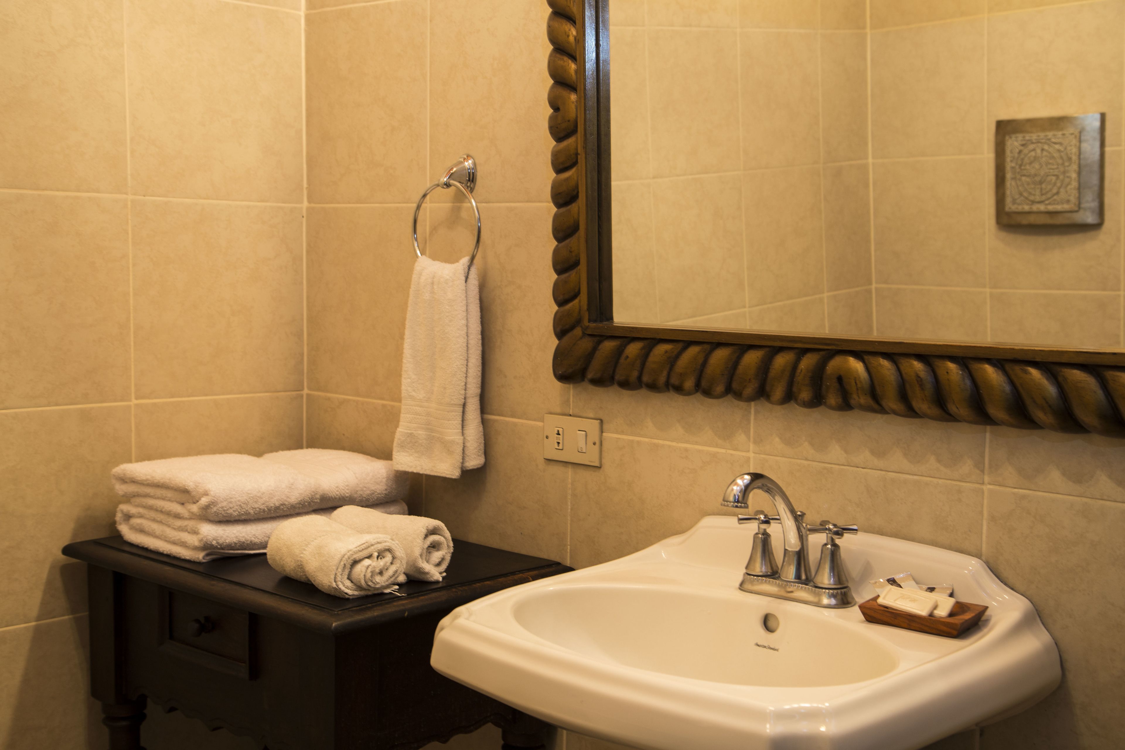 A bathroom with a sink, mirror, and towel rack.