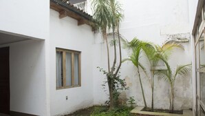 Ein Innenhof mit einer weißen Mauer, einem Fenster und einem Pflasterweg.