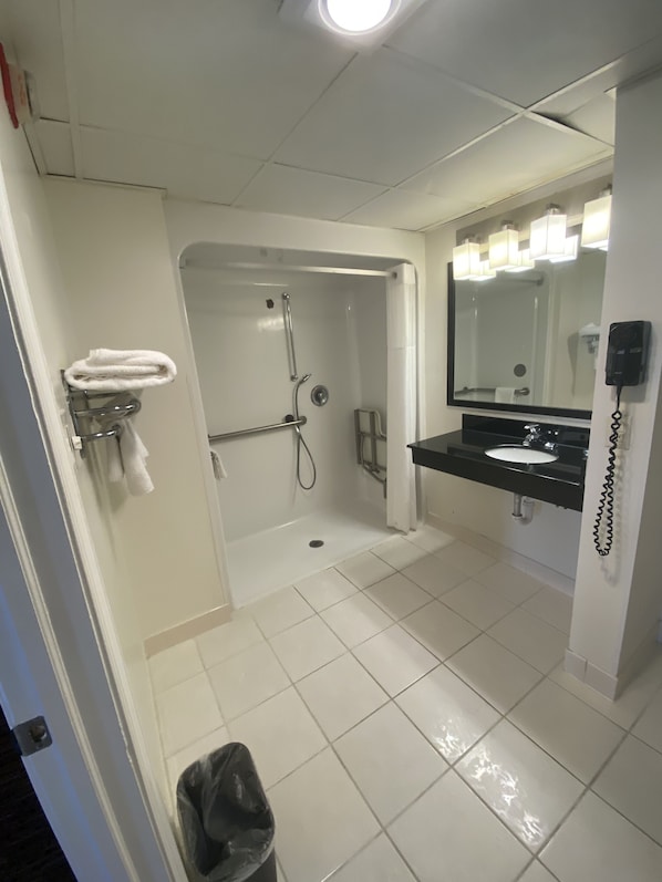 Un baño moderno con cabina de ducha, lavamanos y espejo.