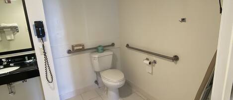 A small, clean bathroom with a toilet, a sink, and a mirror.