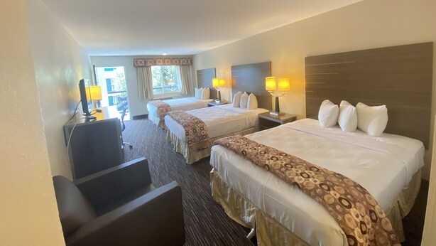 A hotel room with two beds, a desk, and a chair. There are lamps on the bedside tables and a window with curtains. - Garden State Inn (Absecon)
